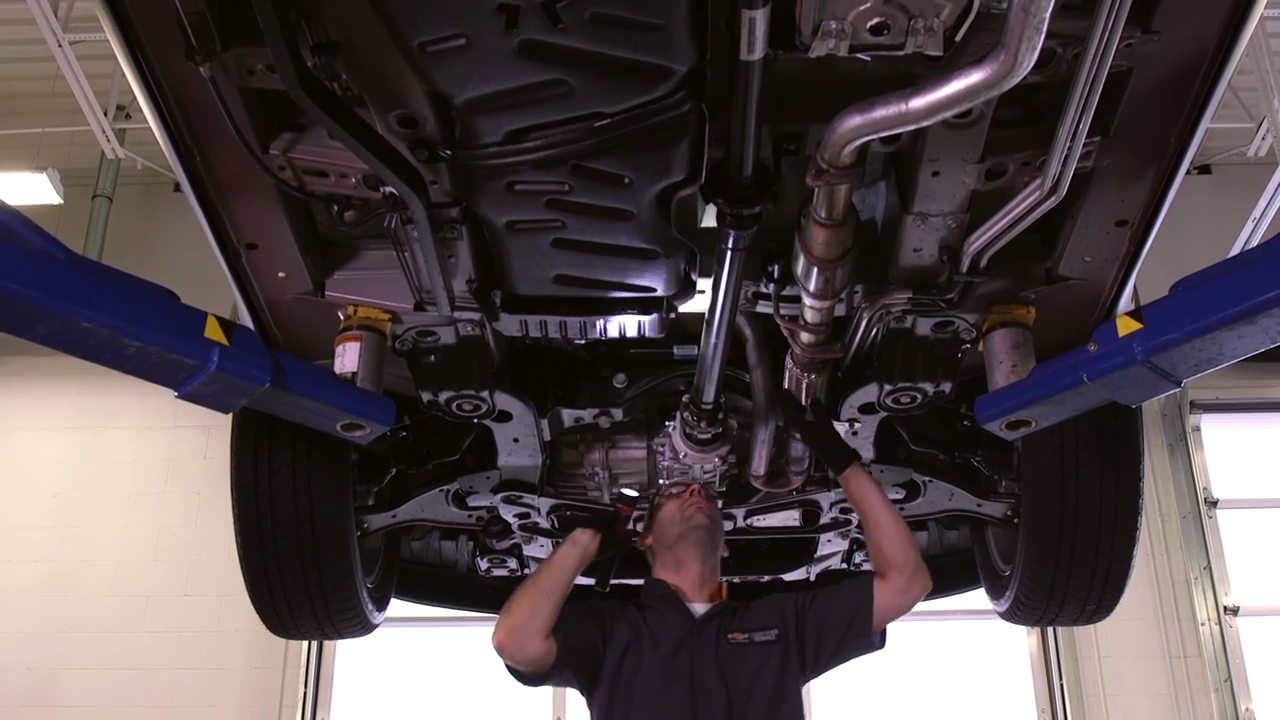 
Mechanic inspecting the undercarriage of a car on a lift in a service bay.