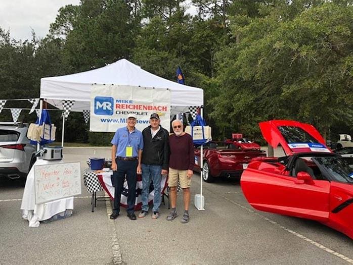 Three men pose by the Mike Reichenbach Chevrolet event tent
