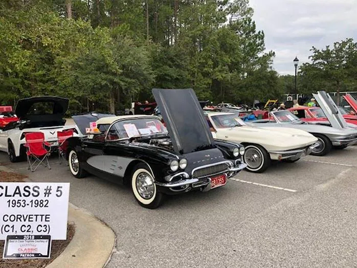 Black classic Corvette with hood open, displayed at car show