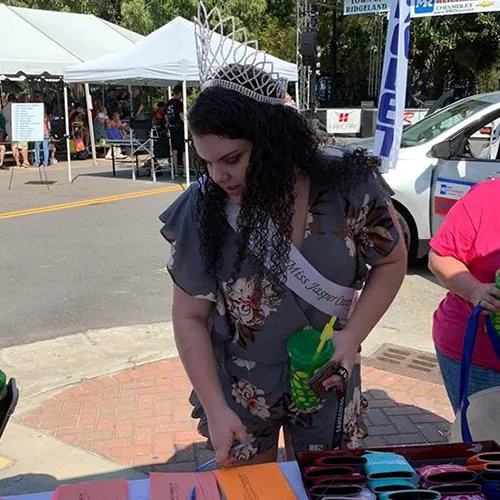 Woman wearing a dark hat and dark clothing stands at the festival