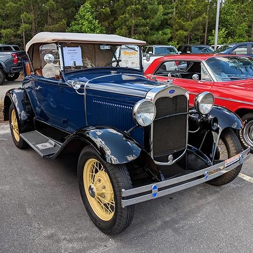 Front of a vintage blue and black convertible car with yellow wheels